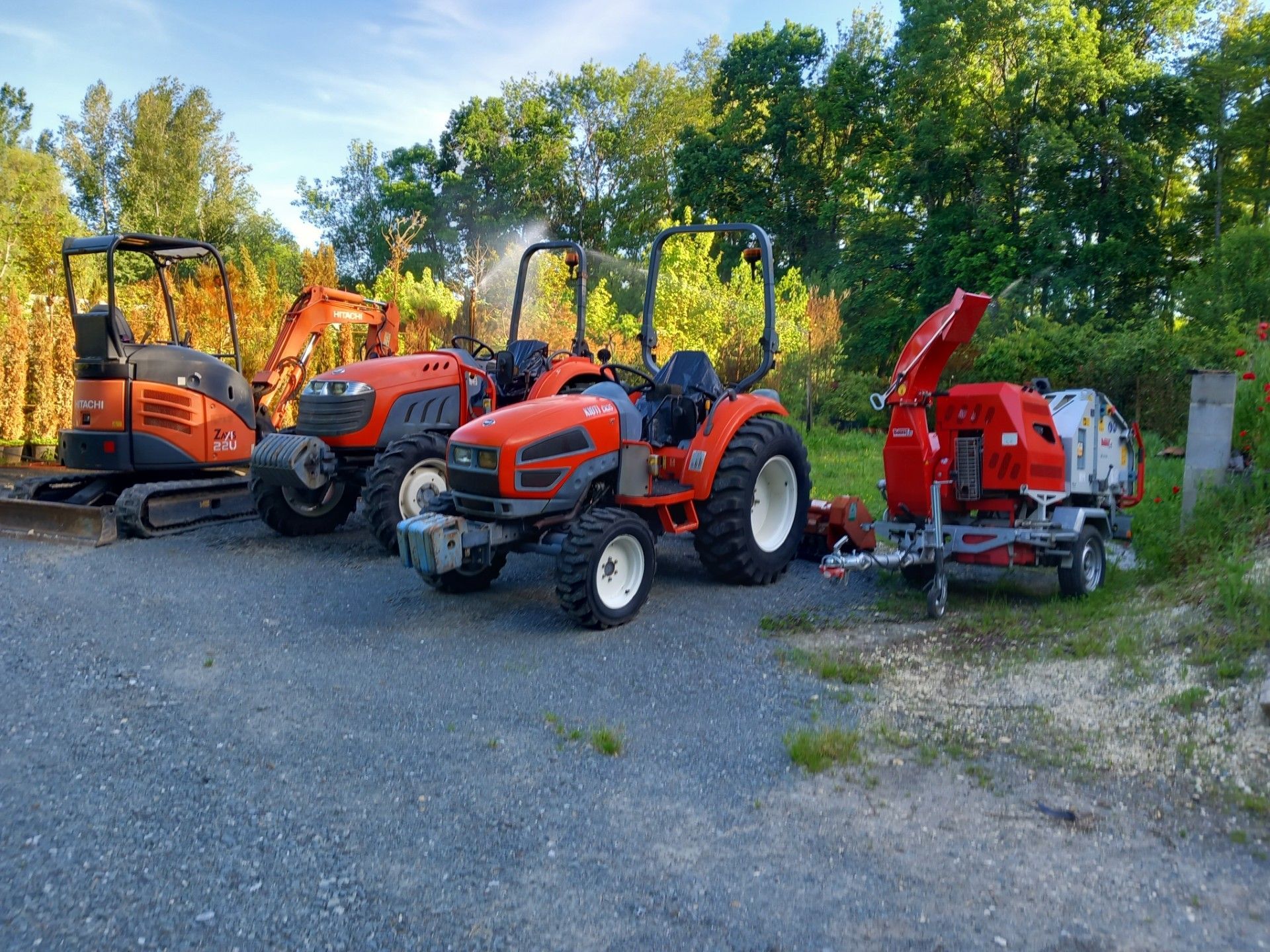 Photo d'une mini-pelle, deux tracteurs et un broyeur