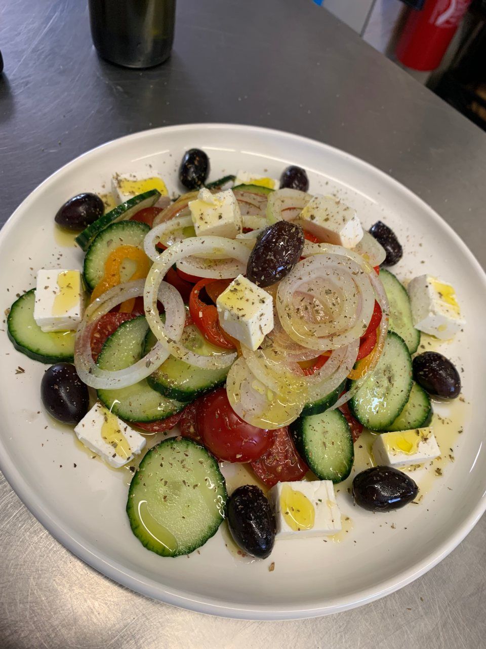 Une assiette blanche garnie d'une salade de légumes et d'olives
