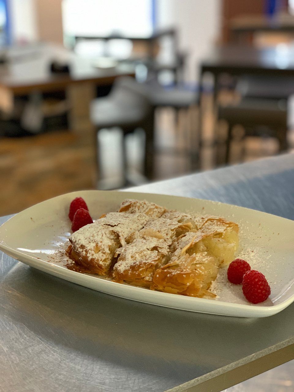 Une assiette de nourriture avec des framboises et du sucre en poudre sur une table.