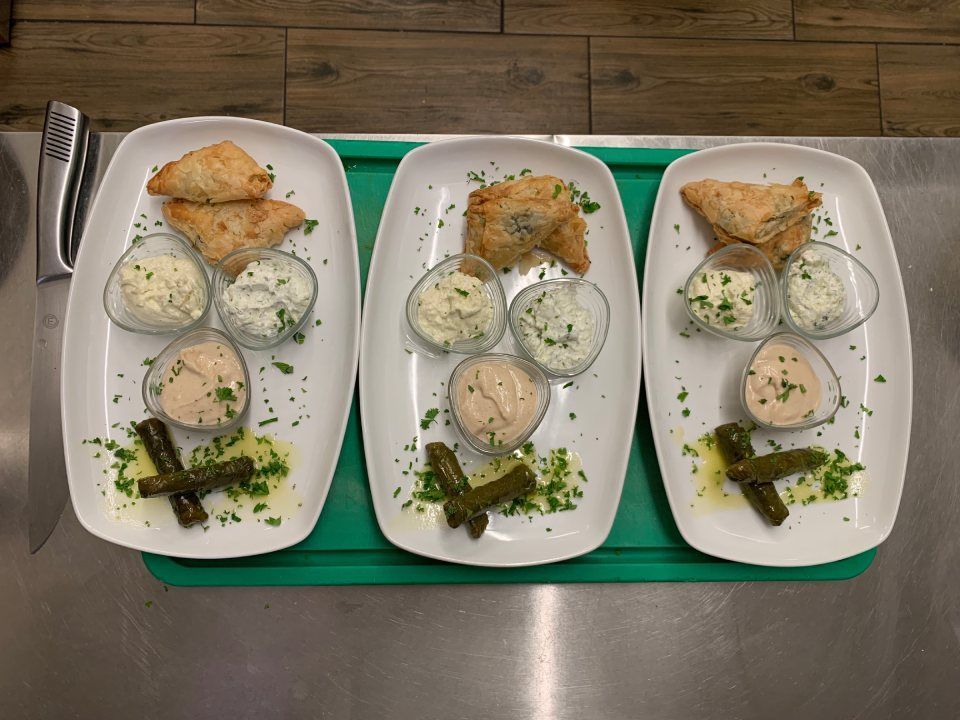Trois assiettes de nourriture sont posées sur un plateau vert sur une table.