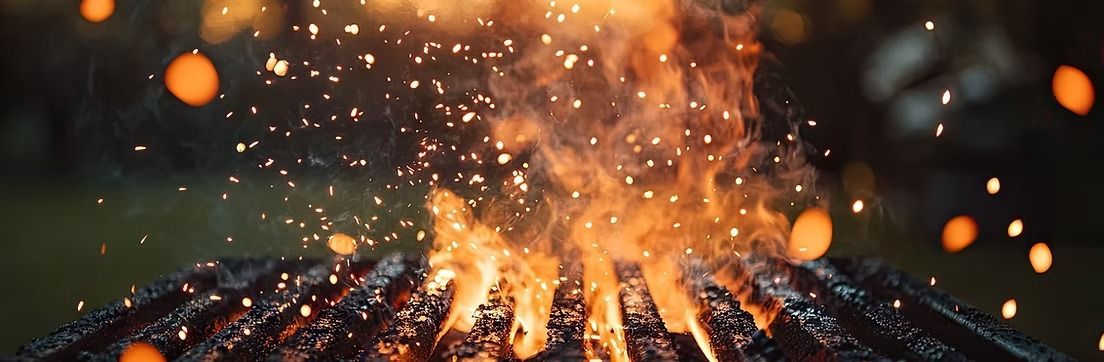 Helle Lagerfeuerflammen und Funken steigen nachts aus einem Bett glühender Kohlen auf