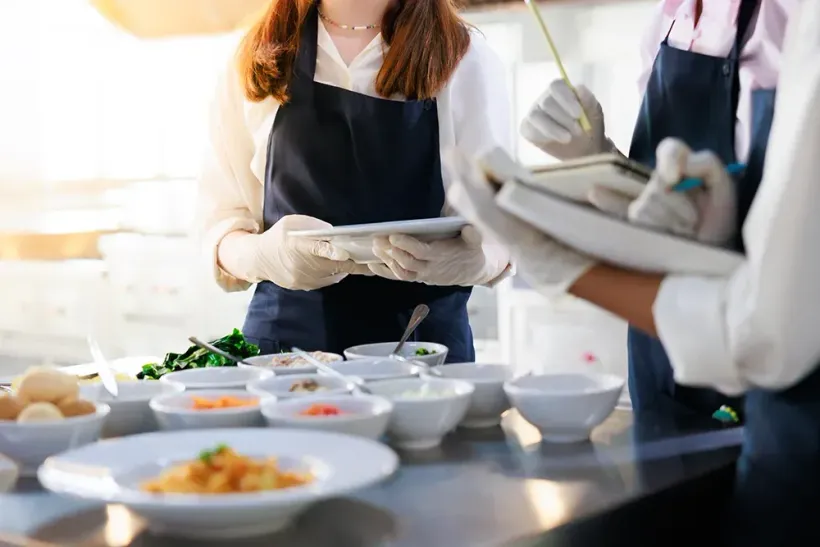 Caterer richten in einer hellen Küche Teller an einem Buffet an