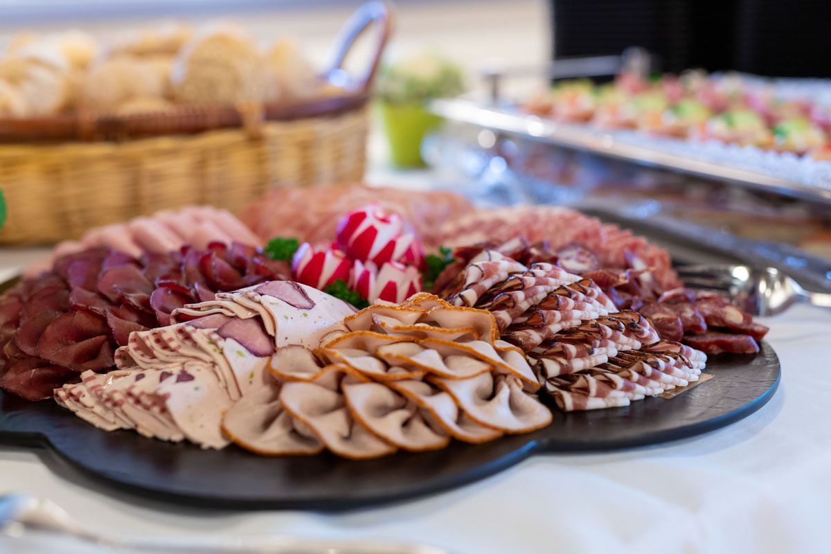 Platte mit verschiedenen Aufschnitten und Käsesorten, angerichtet auf einem Buffet
