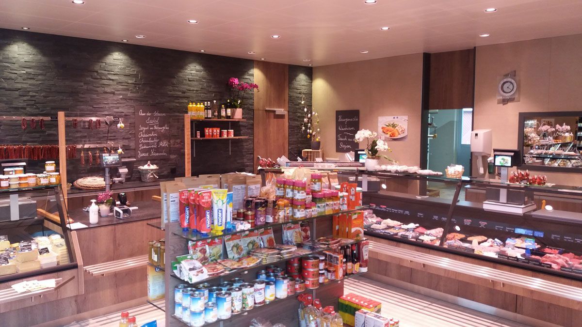 Innenraum einer Bäckerei mit Glasvitrinen, Snackregalen und warmer Beleuchtung