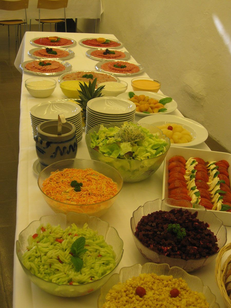 Buffet mit verschiedenen Salaten und Speisen, angerichtet in Schüsseln und auf Platten