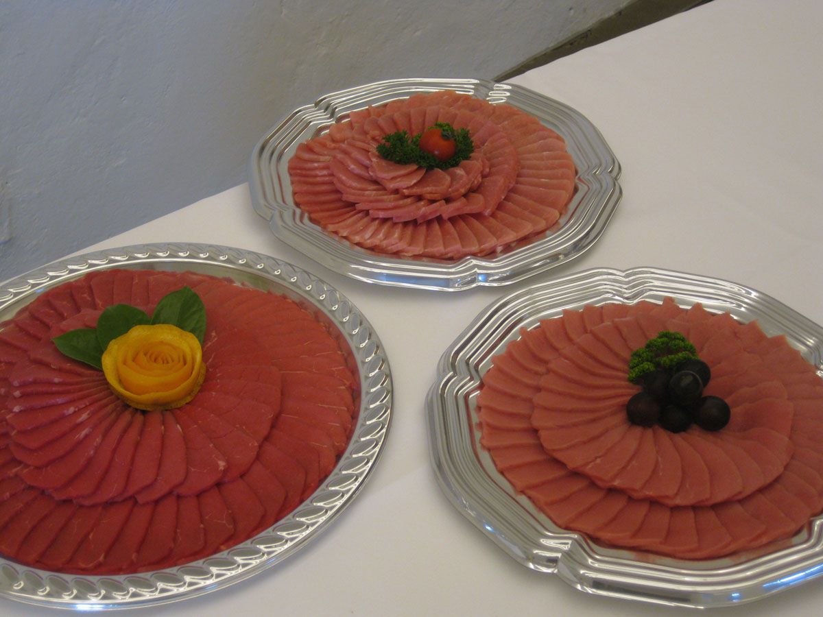 Drei Teller mit rosa glasierten Kuchen, jeweils mit Früchten garniert, auf einem weißen Tisch angeordnet