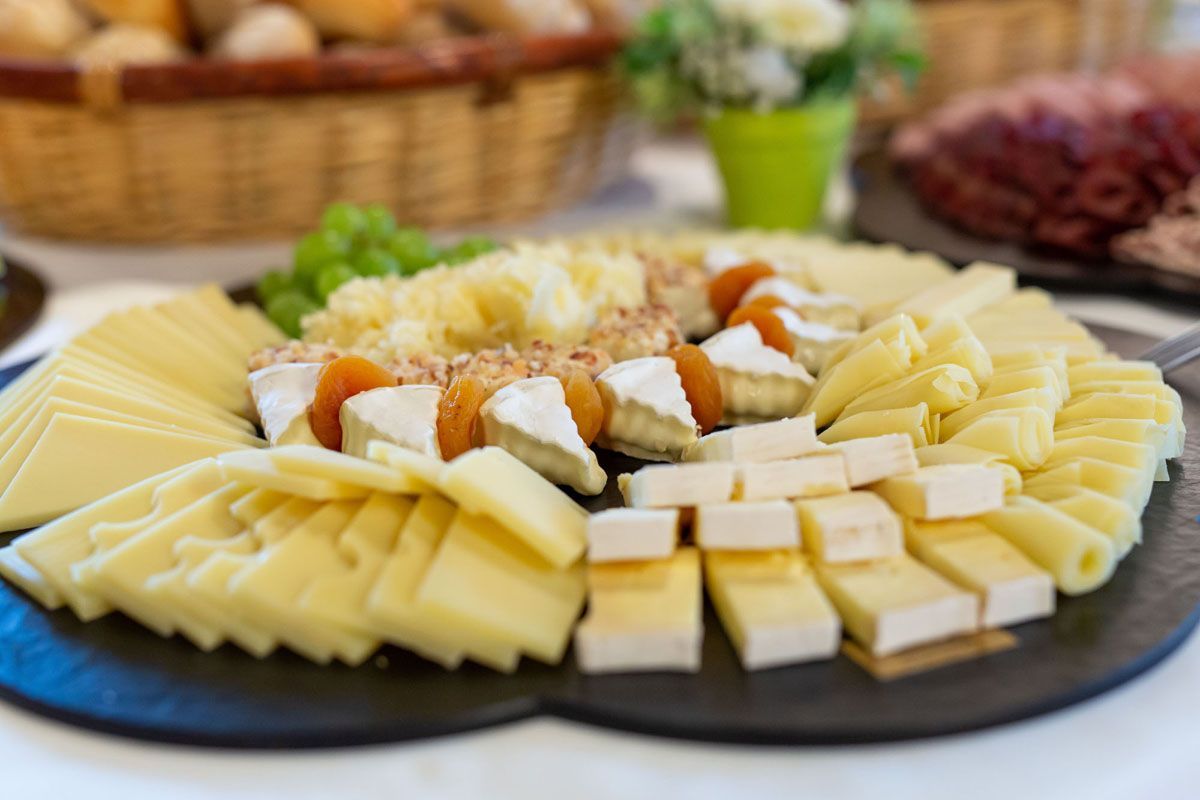 Käse- und Obstplatte auf einem dunklen Serviertablett mit Crackern und Brotscheiben angerichtet