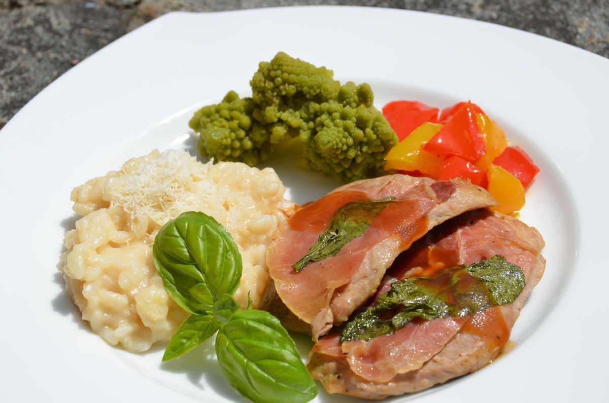 Gourmetgericht mit aufgeschnittenem Fleisch, cremigem Risotto, grünem Gemüse und gerösteten roten Paprika