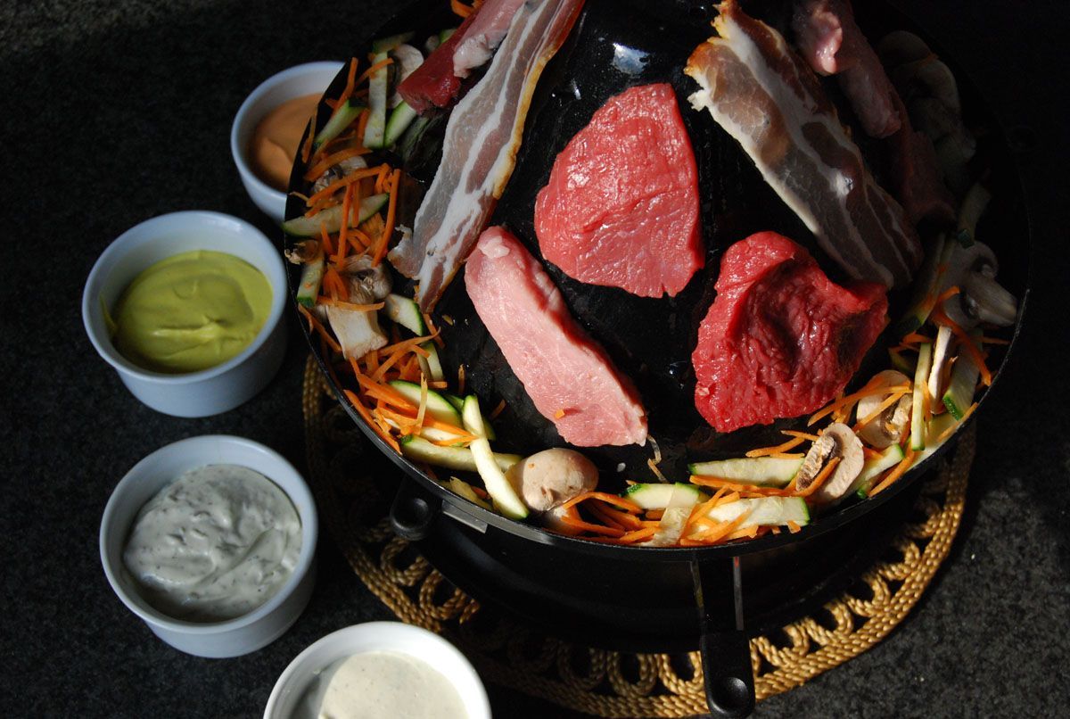 Koreanischer BBQ-Grill mit Rindfleischscheiben und Gemüse, serviert mit kleinen Dip-Schälchen