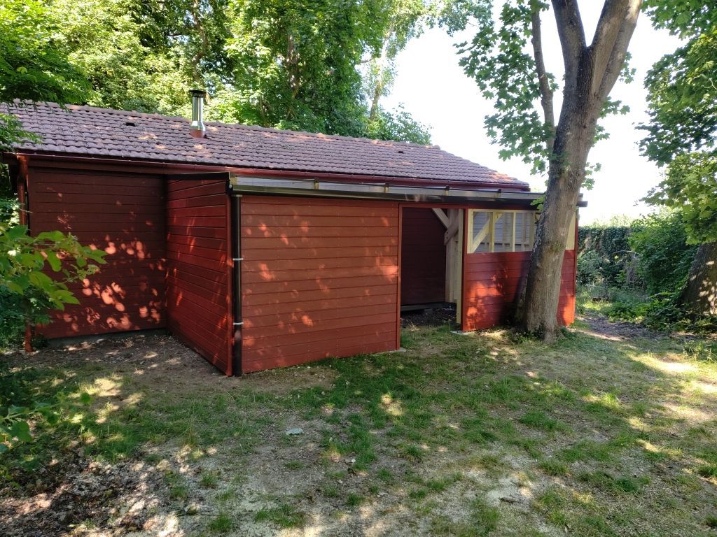 Un petit cabanon en bois rouge, au toit de bardeaux sombres.