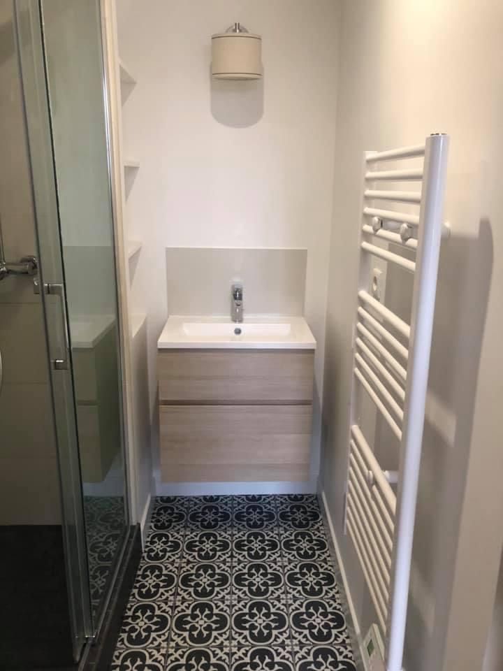 Salle de bains rénovée avec une douche, un lavabo et un porte-serviettes chauffant