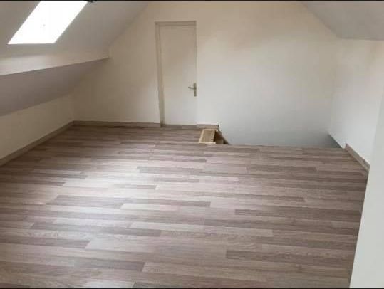 Pièce sous le toit rénovée avec un parquet flottant au sol