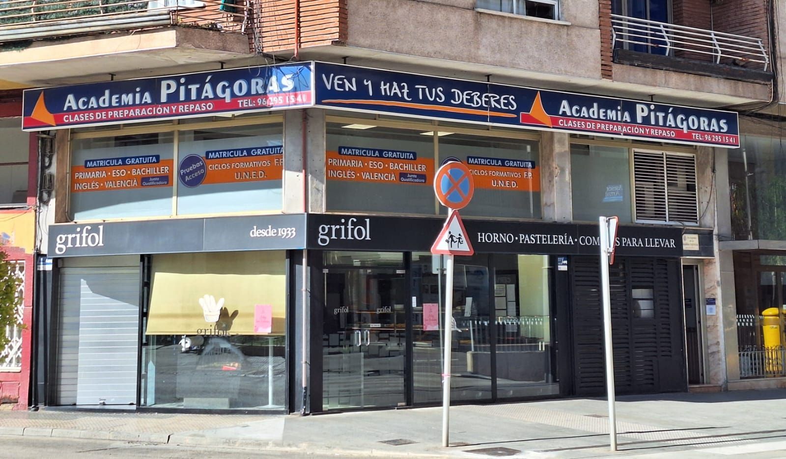 Fachadas de la Academia Pitágoras y Grifol. Señalización naranja y azul. Edificios en una calle, de día.