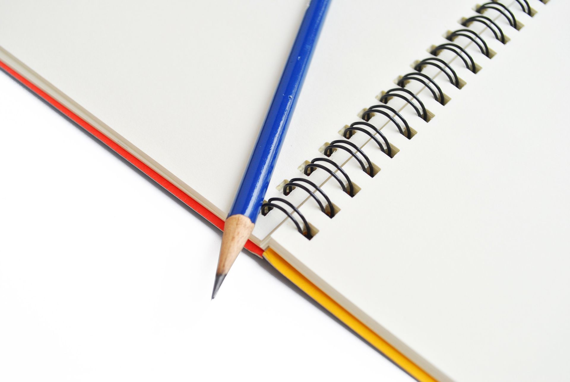 Adolescente con suéter teñido anudado concentrado escribiendo en un escritorio, con una computadora portátil cerca.