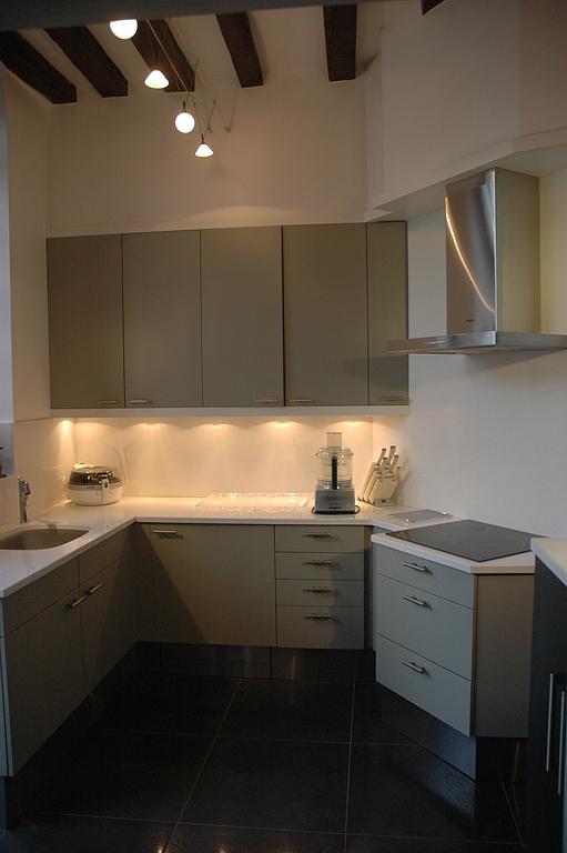 Cuisine moderne et minimaliste avec placards gris, sol noir et éclairage sous les meubles hauts.