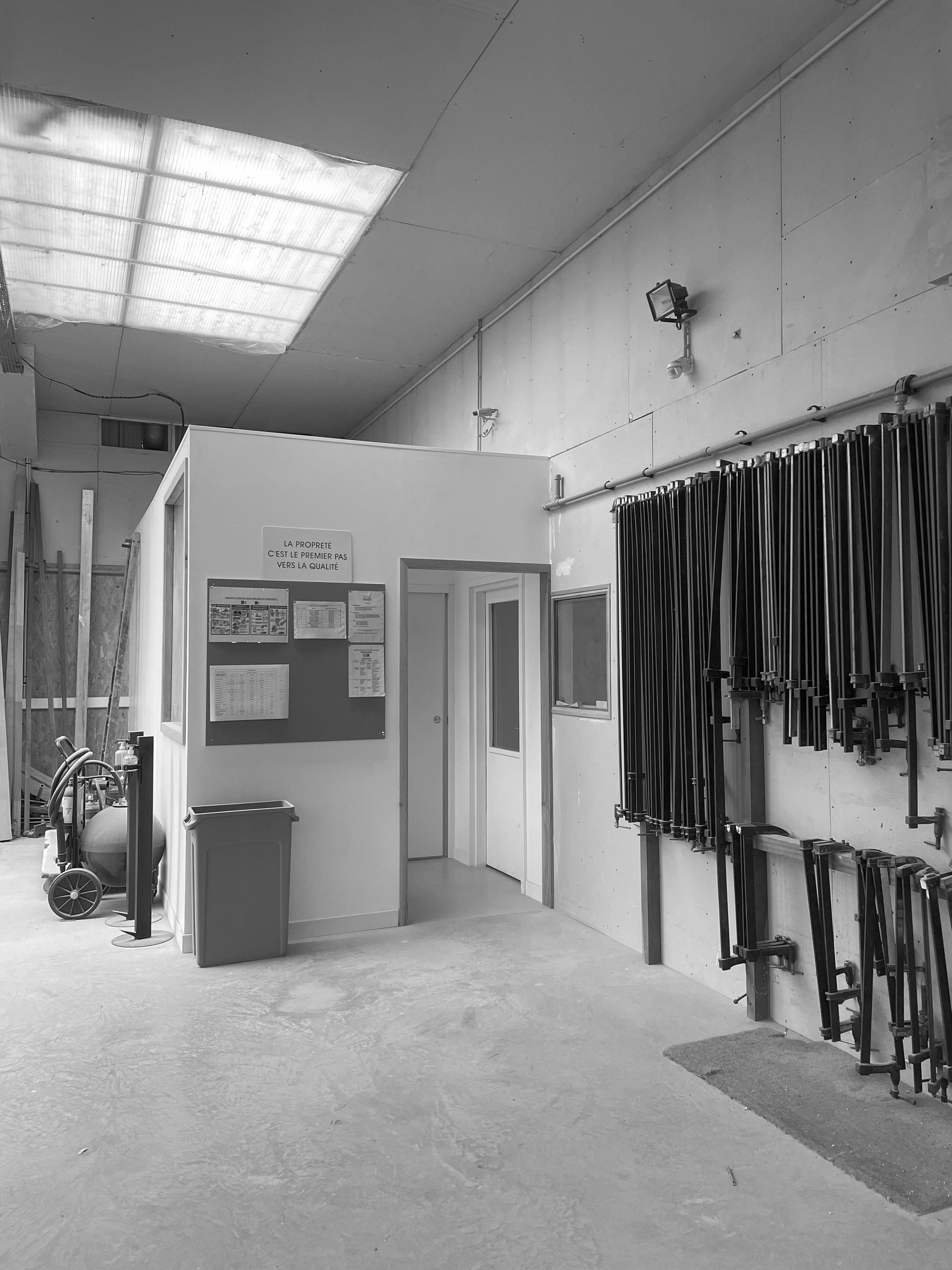 Intérieur d'un atelier avec outils suspendus et un petit coin bureau.