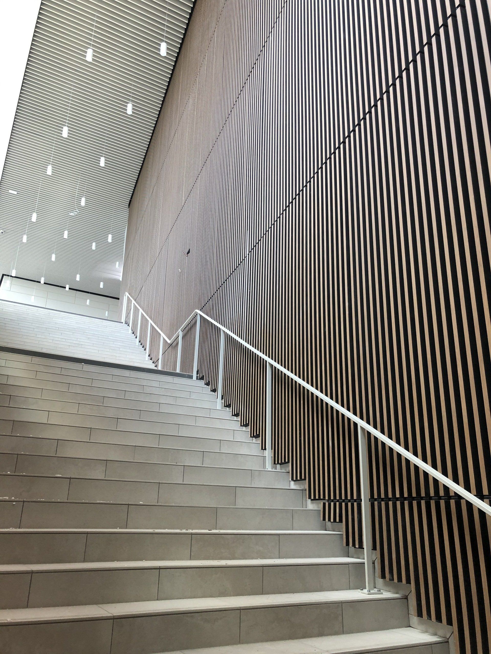 Escalier avec mur en revêtement bois et rampe en métal.