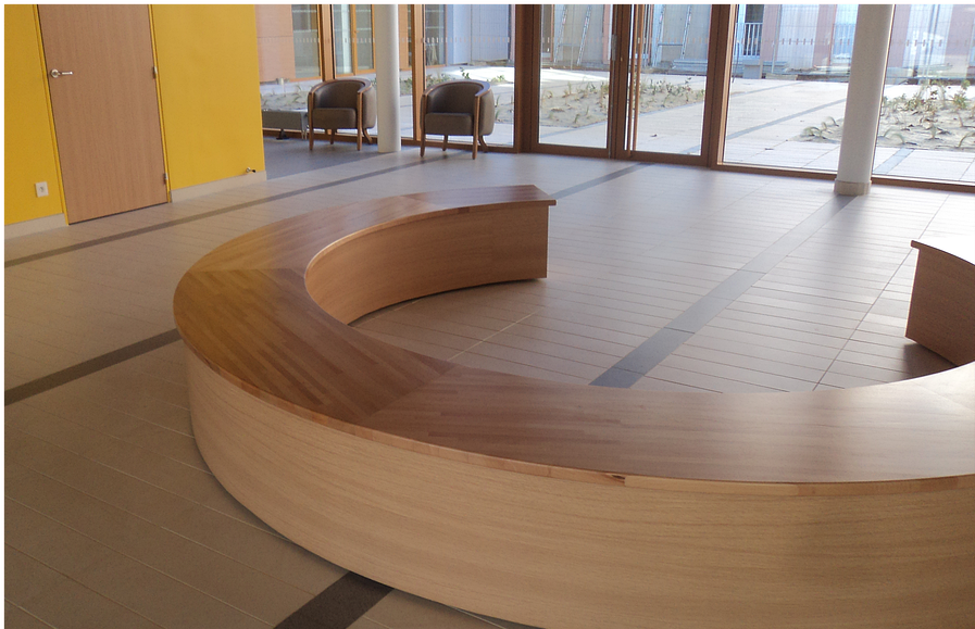 Banc en bois courbé dans un hall d'entrée avec portes vitrées et carrelage clair.