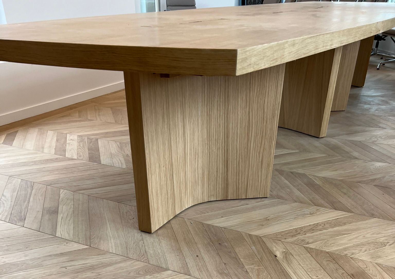 Table basse en bois à pieds inclinés sur un parquet à chevrons.