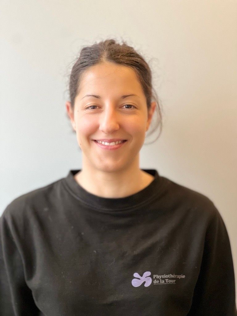 Femme aux cheveux bruns souriante, portant un t-shirt noir avec un logo violet.