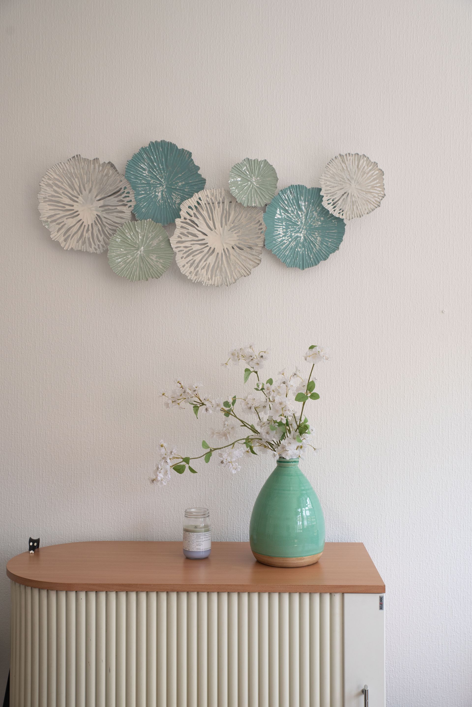 Décoration murale composée de formes circulaires turquoise et blanches.