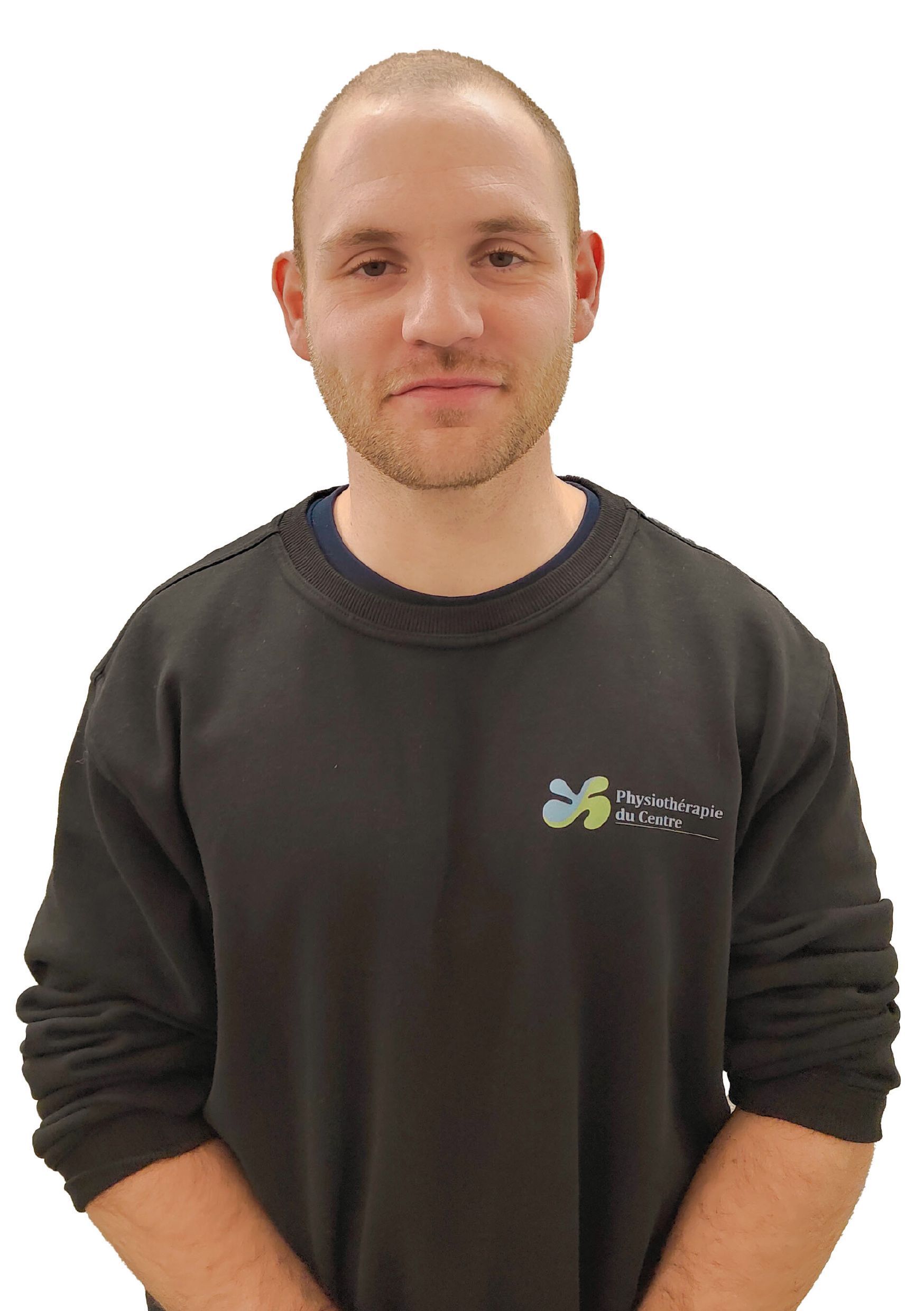 Un homme aux cheveux courts et à la barbe naissante, vêtu d'un sweat-shirt foncé, sourit à l'objectif.