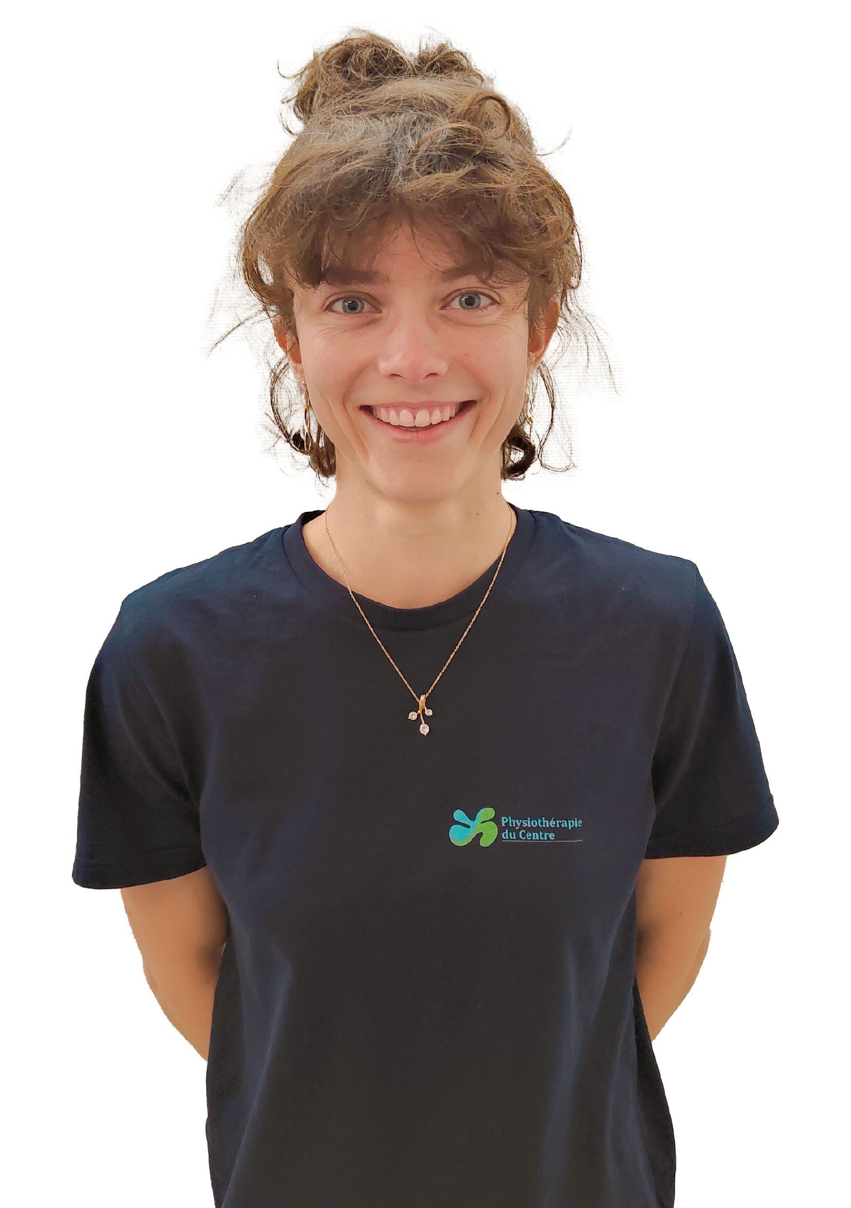 Femme aux cheveux bruns relevés en chignon, souriante, portant un t-shirt bleu foncé.