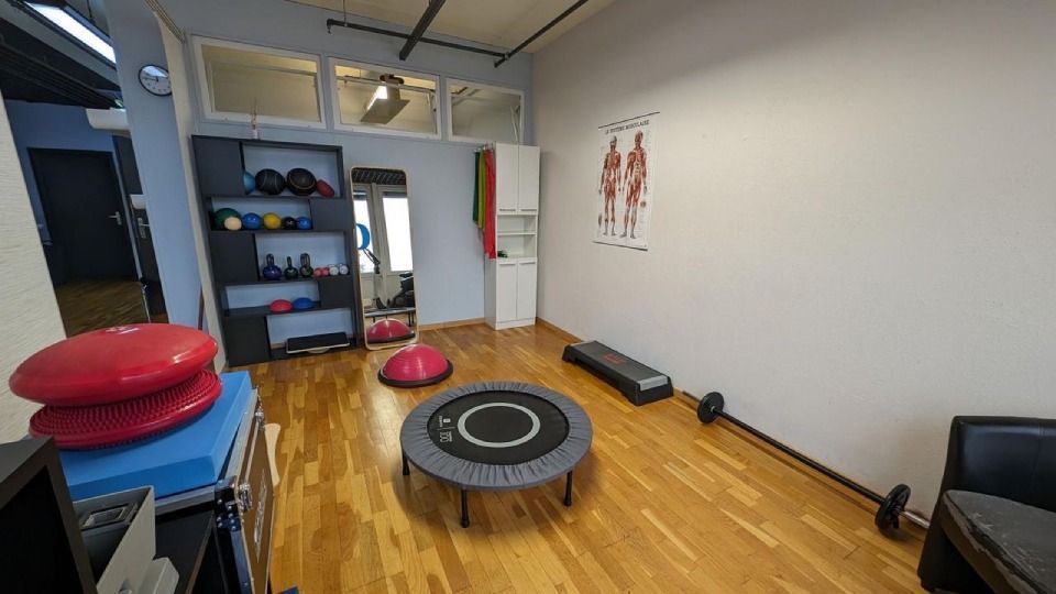 Un studio de fitness avec des équipements de musculation sur parquet : haltères, disques d’équilibre, trampoline et step.