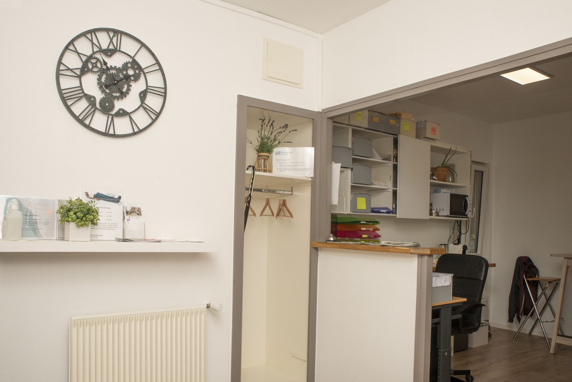Espace d'accueil avec horloge, étagères et petites plantes.