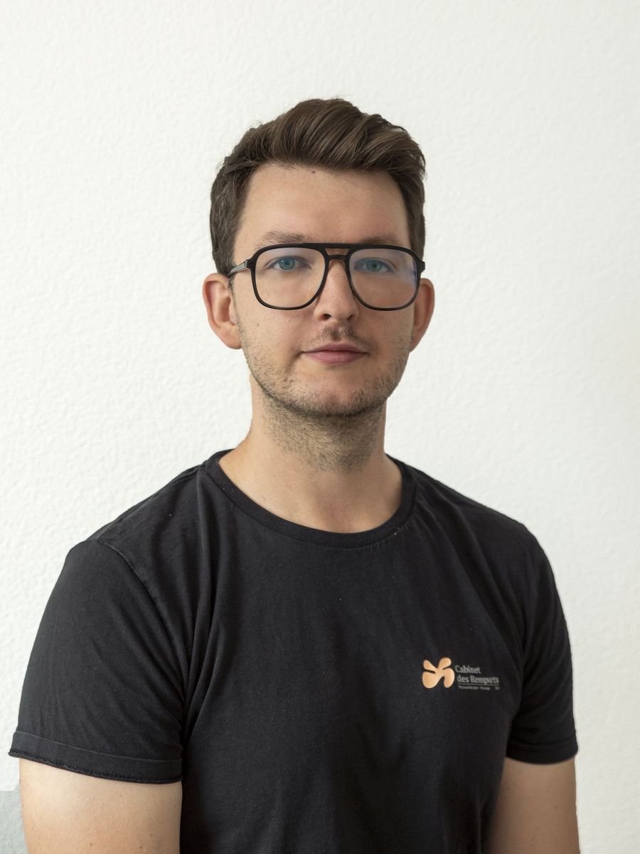 Homme à lunettes portant une chemise noire, regardant l'objectif. Fond blanc.