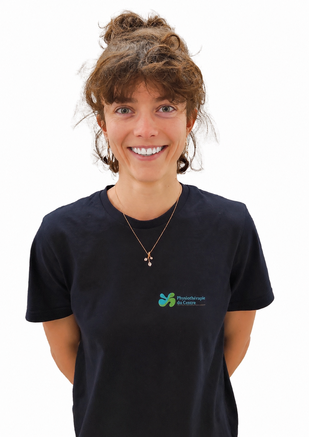 Femme aux cheveux bruns relevés en chignon, souriante, portant un t-shirt bleu foncé.