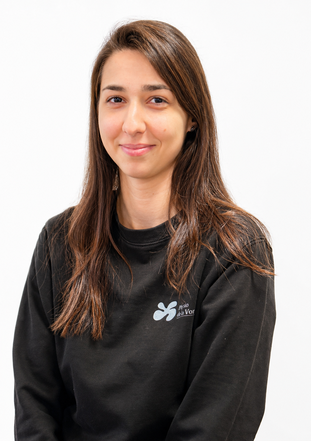 Femme aux longs cheveux bruns, souriante, portant un sweat-shirt noir orné d'un petit emblème bleu clair.
