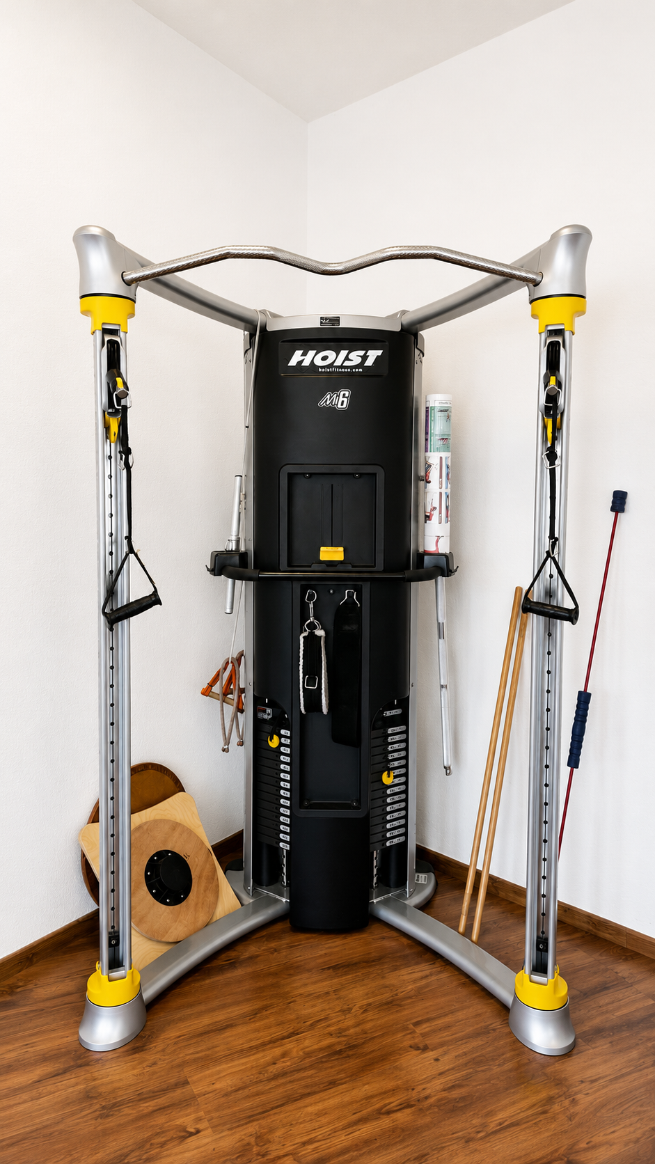 Appareil de fitness d'angle, noir et argent avec des touches de jaune, entouré d'accessoires sur un parquet