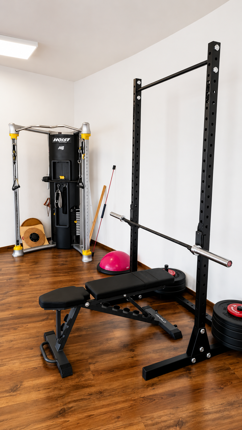Salle de sport à domicile avec banc de musculation, rack à squats, machine à câbles et équipements de fitness sur parquet