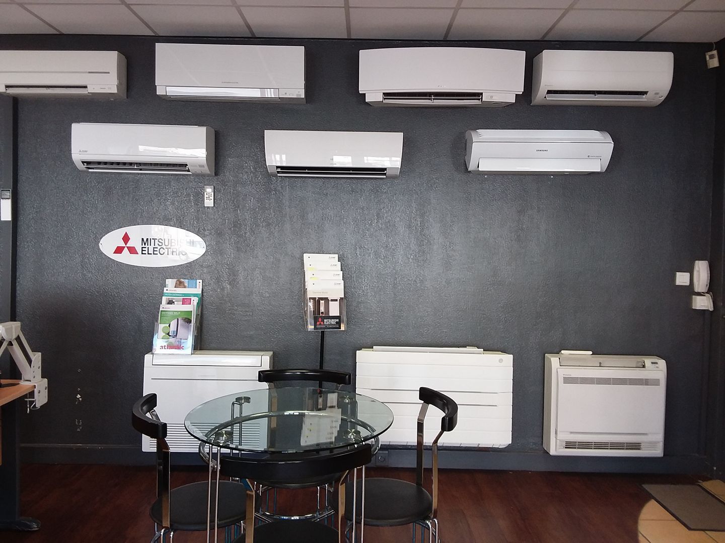 Espace d'accueil avec bureau en verre, chaises, climatiseurs muraux.