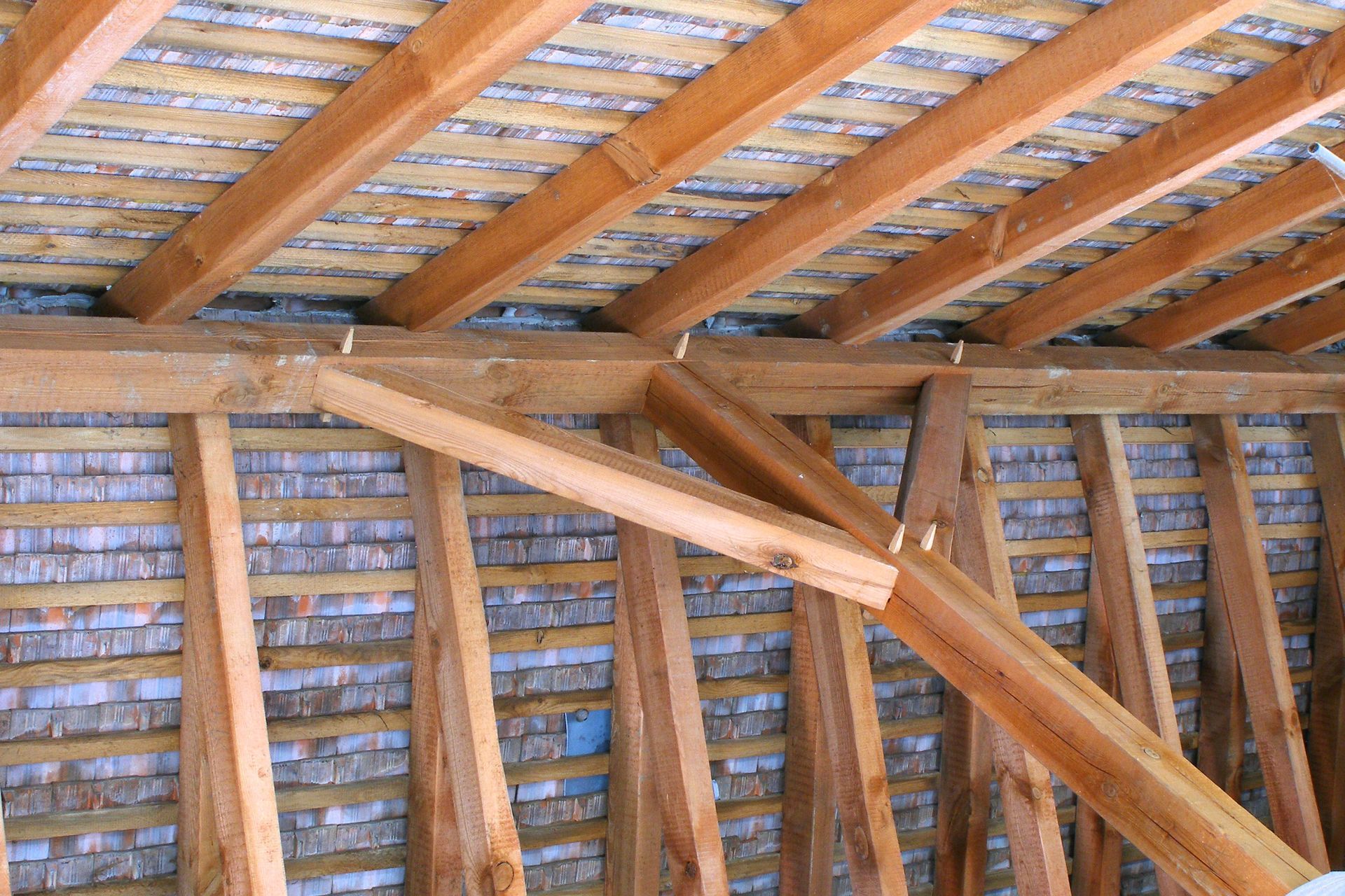 Charpente et chevrons en bois d'un bâtiment, vue intérieure, supports inclinés.