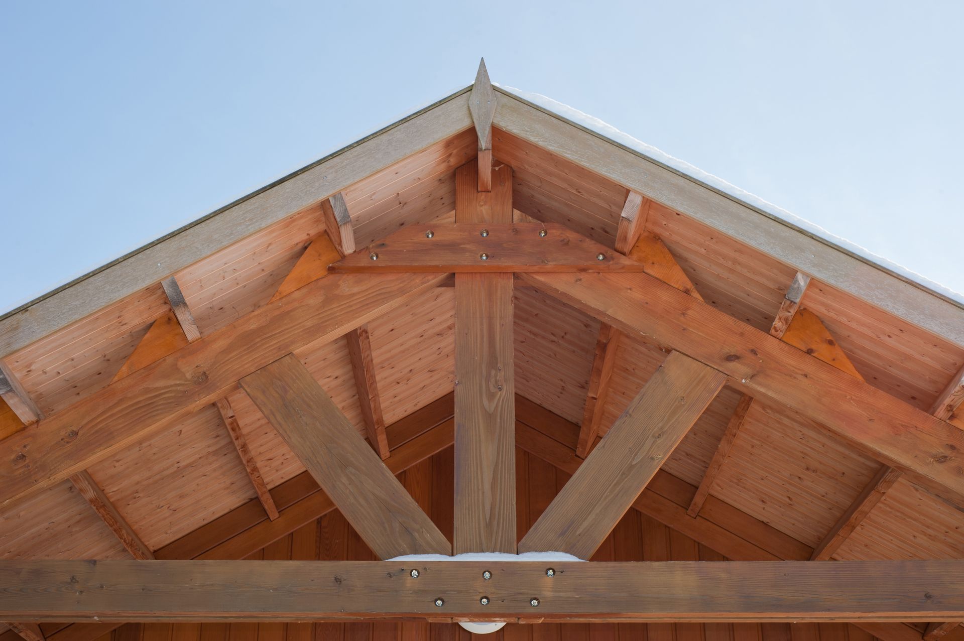 Charpente de toit en bois sur fond de ciel bleu.