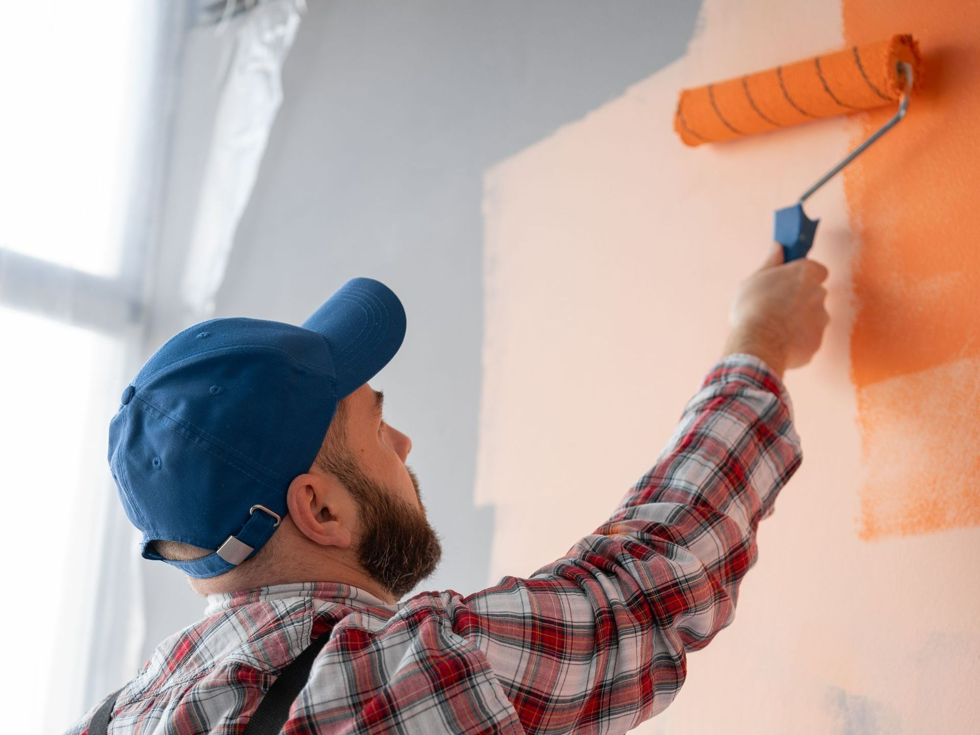 Jeune homme peignant une maison bleue sur un mur blanc