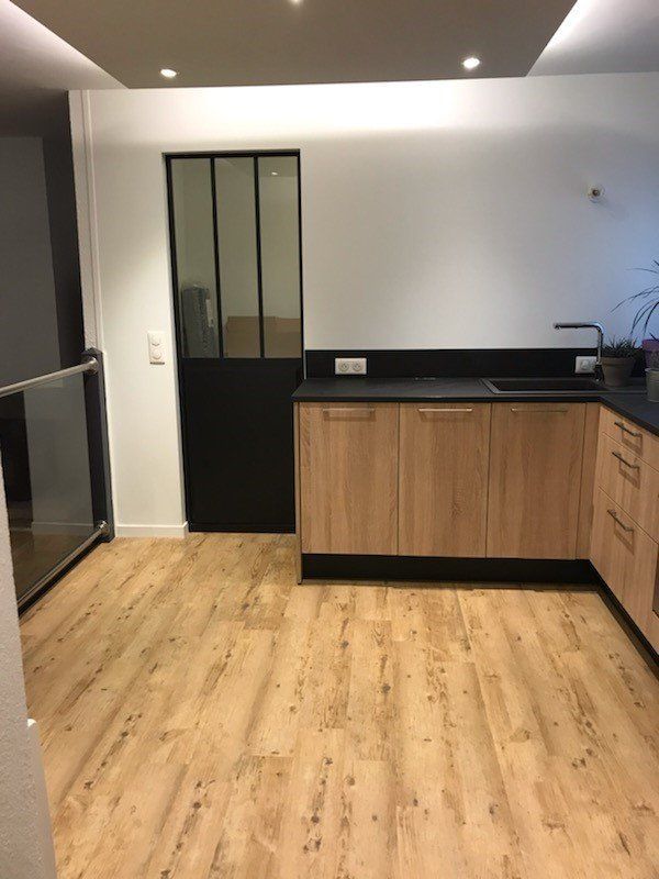 Cuisine rénovée avec plans de travail sol en bois et porte verrière