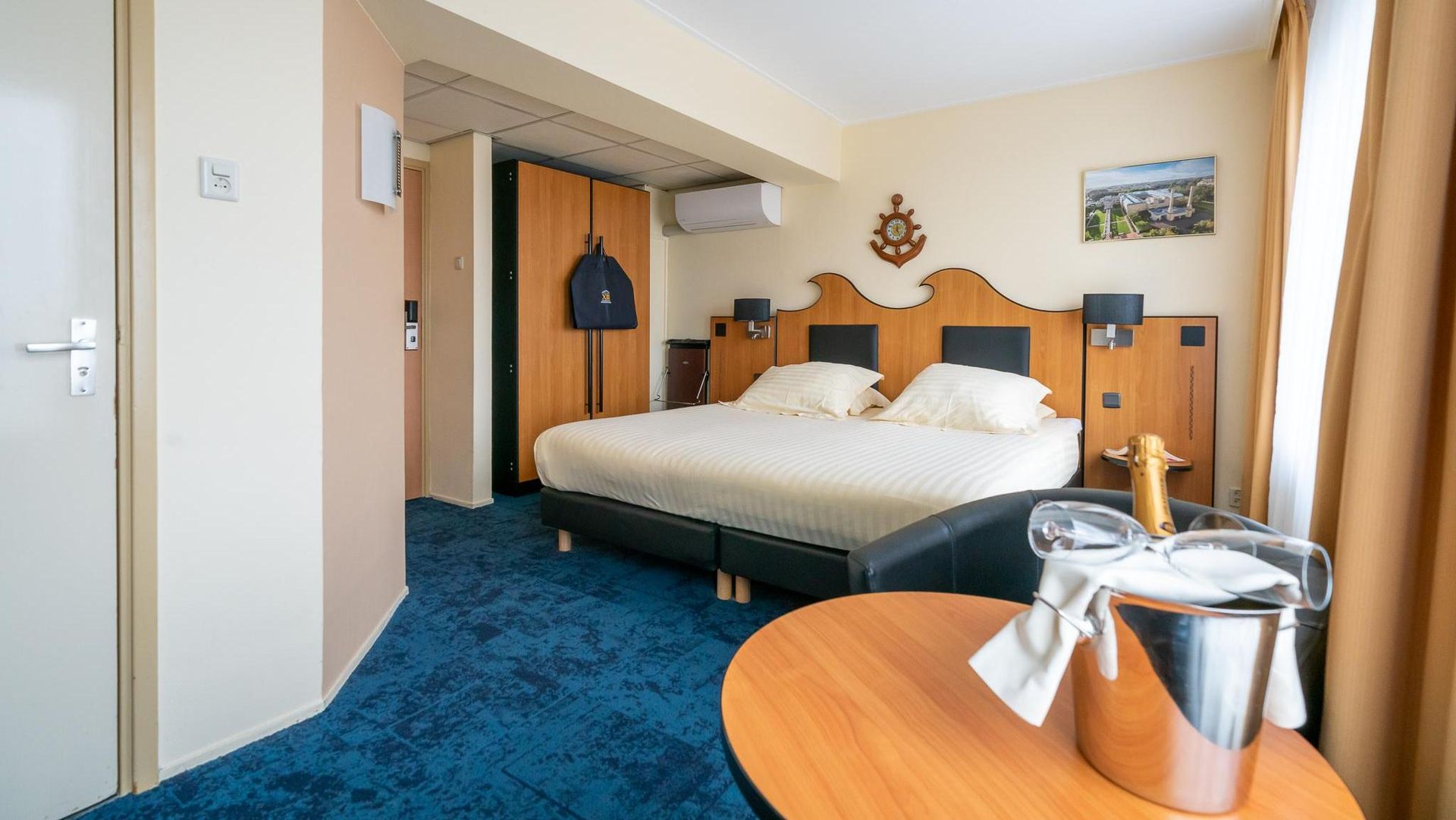 A hotel room with a king size bed and a table with a bucket of champagne on it.