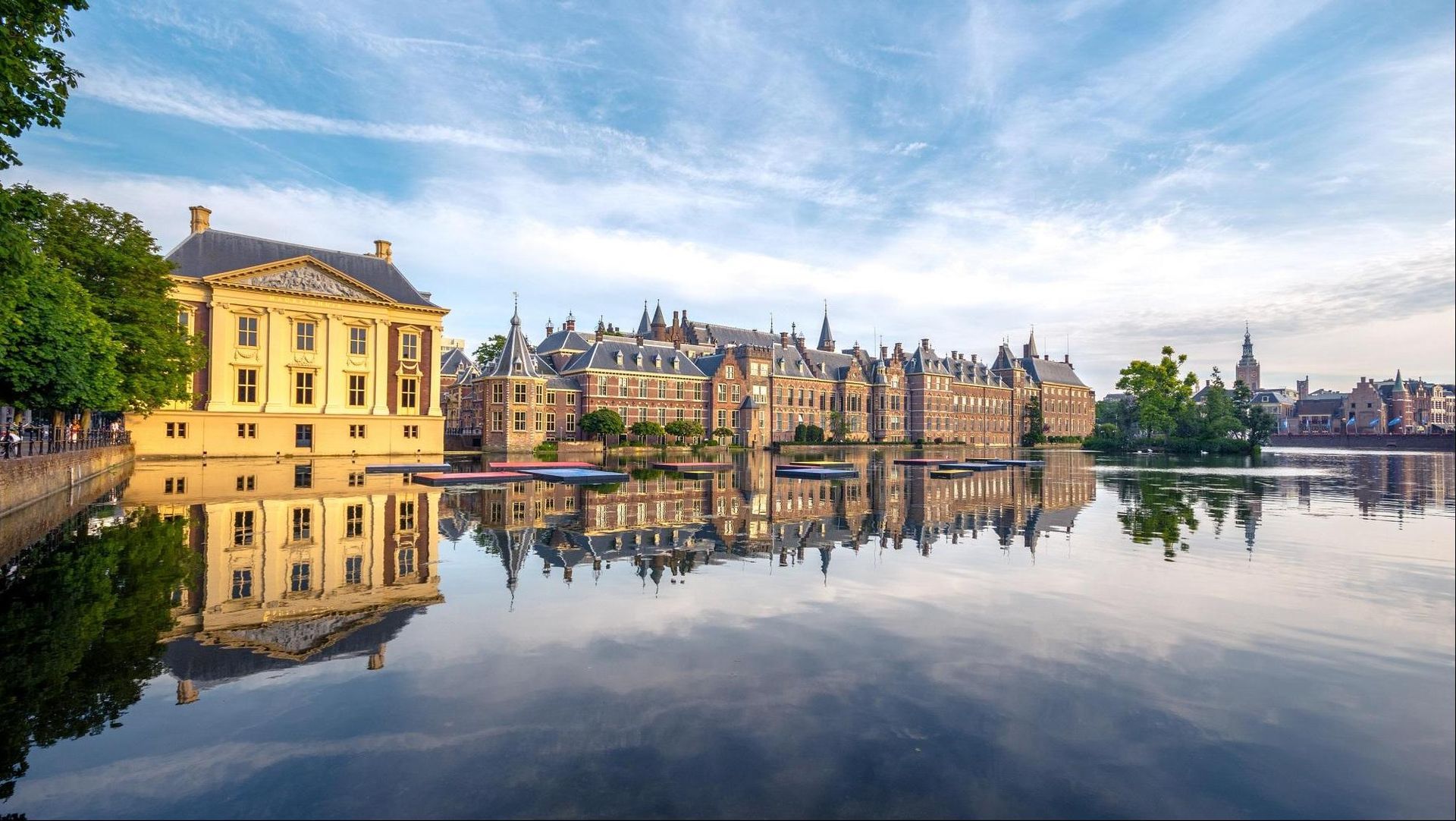 Een groot gebouw wordt weerspiegeld in het water van een meer.