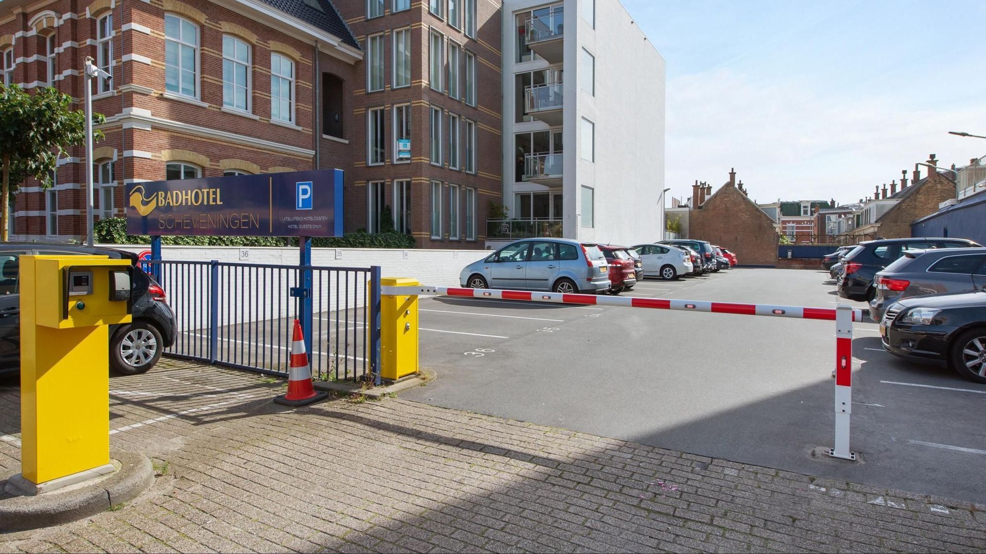 A parking lot with cars parked behind a yellow barrier