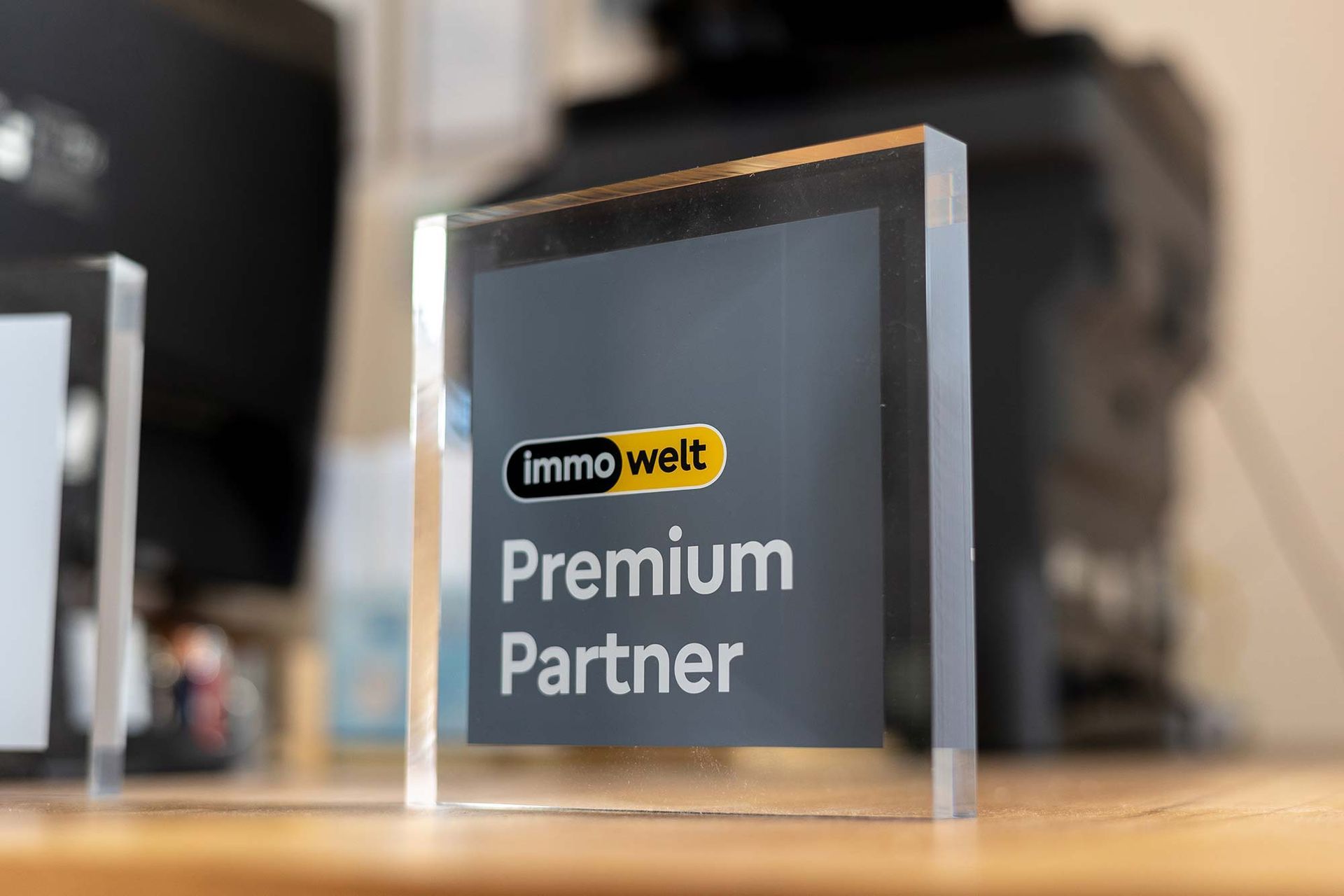 Auf einem Holztisch steht ein Glasblock mit der Aufschrift „Premiumpartner“.