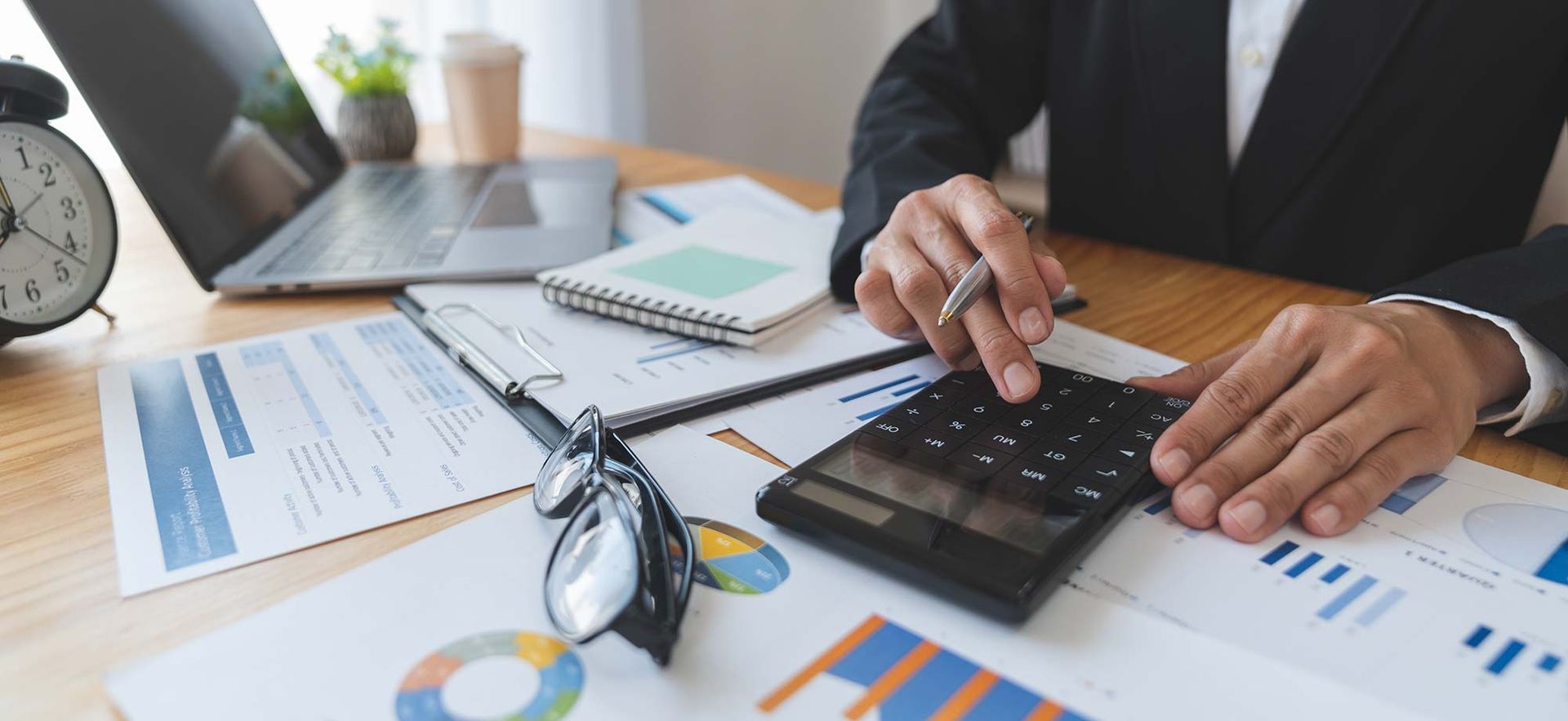 Ein Mann sitzt an einem Schreibtisch und benutzt einen Taschenrechner.