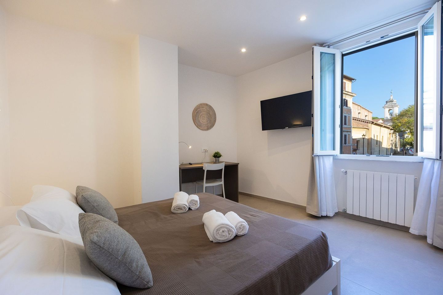 Colosseum Holidays - A hotel room with a bed , desk , television and window.