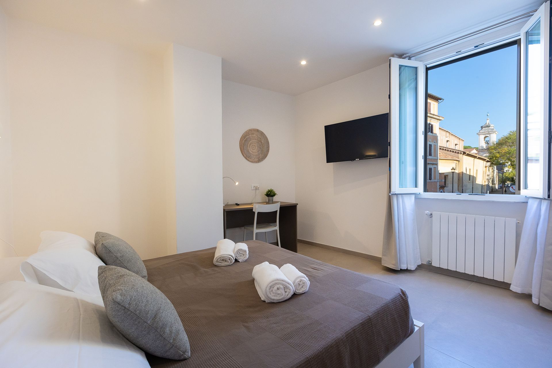 Colosseum Holidays - A hotel room with a bed , desk , television and window.