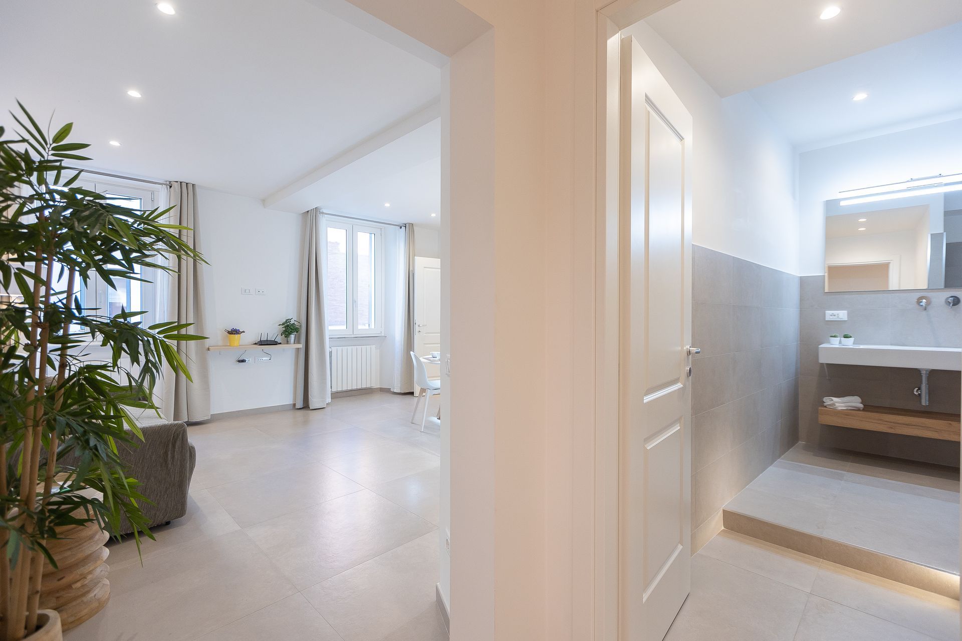 A hallway leading to a bathroom and living room in a house.