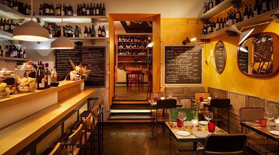 A restaurant with tables and chairs and bottles on the shelves