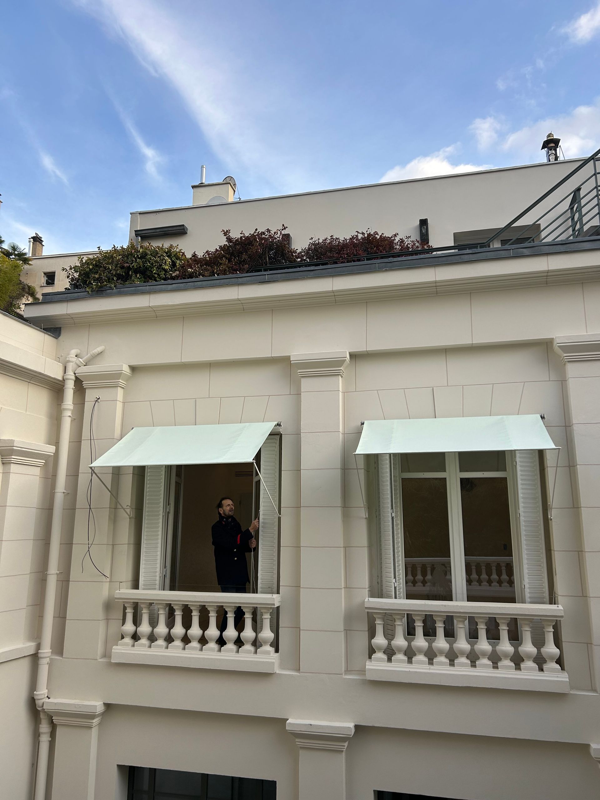 Deux stores blancs en train d'être déployé