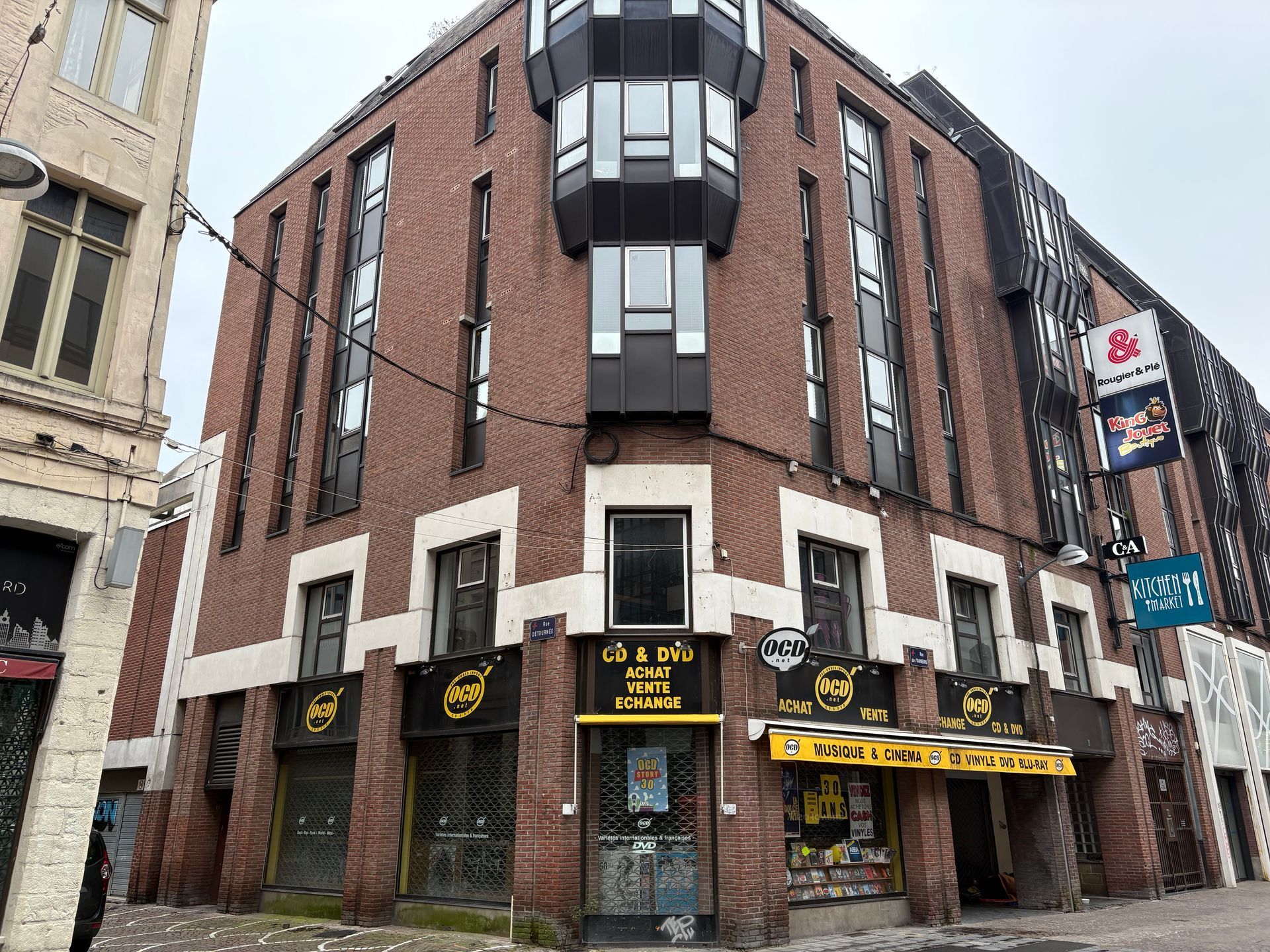 Des stores jaunes et noirs sur un bâtiment en brique rouge